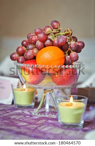 Wedding decorations with fruits arrangement and candles. Arrangement with grapes, orange and apples on wedding ceremony detail. Elegant and colorful wedding arrangement with fruits and candles