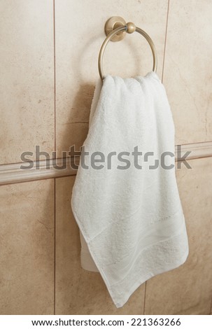 white hand towel on metallic hanger. Close up background of a bathroom hand towel on tile wall.