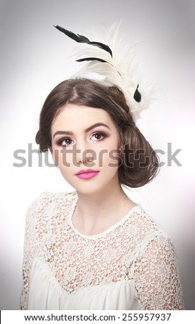 Hairstyle and make up - beautiful young girl art portrait. Genuine natural brunette with creative haircut, studio shot. Attractive female with beautiful lips and eyes in white lace blouse, over white