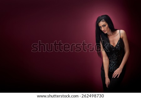 Attractive brunette woman in a black posing dramatic on purple background. Long hair female art portrait, studio shot. Genuine natural dark hair girl with sad look. Slim young woman posing indoor