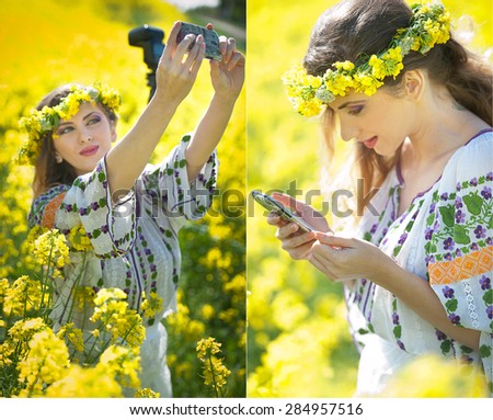 Woman wearing Romanian traditional blouse taking a selfie with a camera and checking her smart phone in canola field, outdoor shot. Portrait of beautiful blonde enjoying the yellow flowers of rapeseed