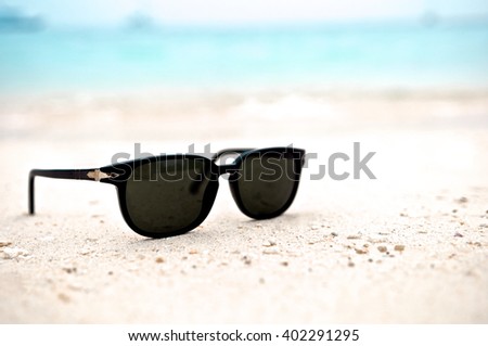 Fashion sunglasses on the beach near the blue sea. Sand and glasses. Summer vacation actually relaxing, Thailand. Close up.