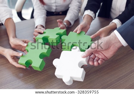 Group of business people assembling jigsaw puzzle and represent team support and help concept in office