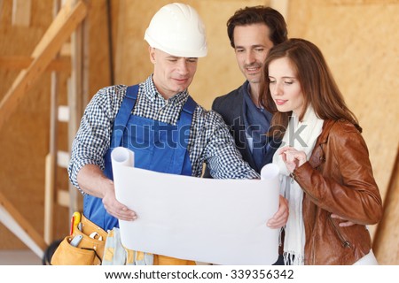 foreman shows house design plans to a young couple