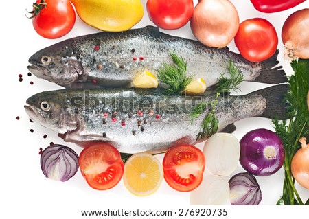 Two fresh rainbow trout with herbs, vegetables and lemon, top view