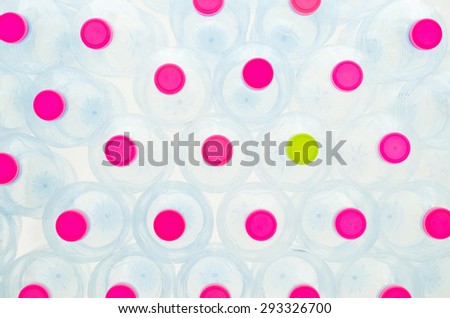 Stack of empty plastic water bottles which only one has green bottle cap and others have pink bottle caps