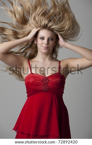 Beautiful blonde teenage girl with flying hair isolated on gray background