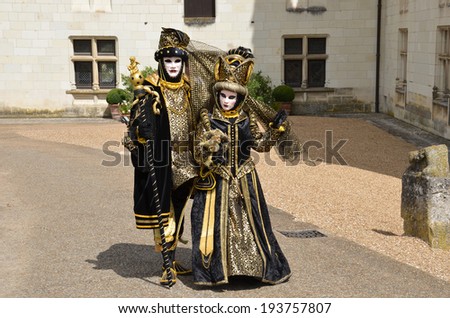Three persons in Venetian masks and costumes