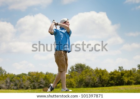 Young male golfer finishing golf swing from tee box