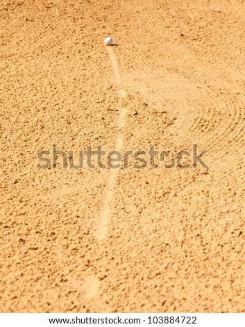 Golf ball rolling into sand trap on golf course