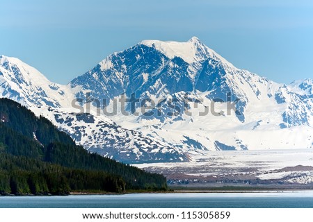 Alaska\'s snow capped mountain range and thick forest along the Inside Passage