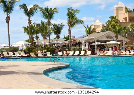GRAND CAYMAN, CAYMAN ISLANDS - MAR. 8:  Luxury resort hotel in Grand Cayman on Mar. 8, 2013.  Guests enjoying the amenities of a large swimming pool and beach access to Seven Mile Beach.