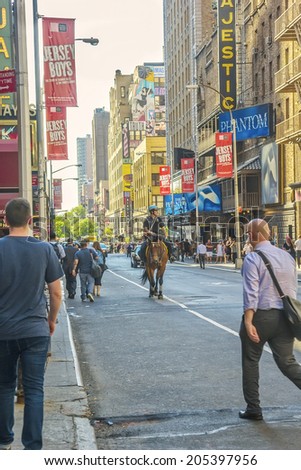 NEW YORK, NY - JUNE 24, 2014: NY Police Officer on horseback rides down the street in Times Square. The NYPD Mounted Unit was created in 1871 and has 112 officers who are part of the unit.