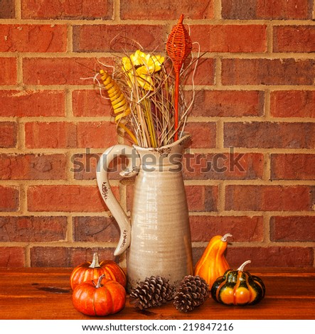 Vintage vase with dried flowers and small pumpkins and gourds make for a autumn harvest display.