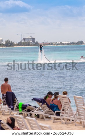 GRAND CAYMAN, CAYMAN ISLANDS - MARCH 8, 2013:  Crowd on beach in Cayman Islands watches an unidentified man using the water Jet Pack on Seven Mile Beach.