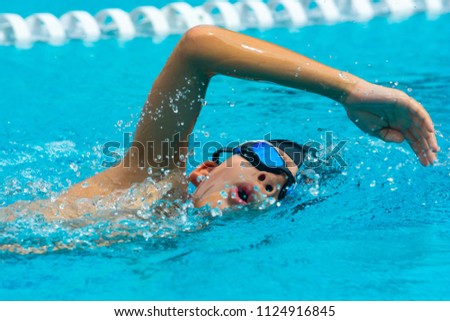 ASIAN BOY WITH GOGGLES EXERCISING FREESTYLE SWIMMING AND BREATHING