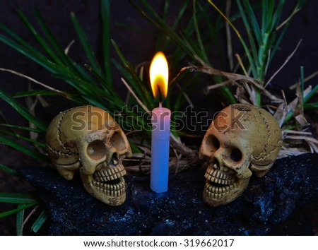STILL LIFE CONCEPT TWO HUMAN SKULLS AND CANDLE LIGHT DARK BACKGROUND