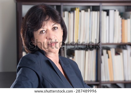 Portrait of a businesswoman in front of a wall of books and papers.