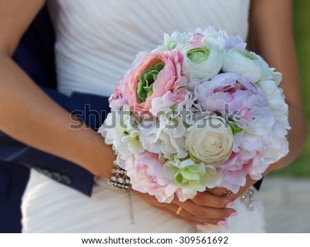 flower bouquet in hands of bride which groom embracing