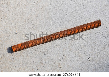 A cut piece of corroded stained rusty metal armature fitting on bubbled concrete floor