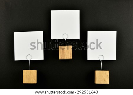Hierarchy - Three white paper notes with wooden holders isolated at black paper background for presentation