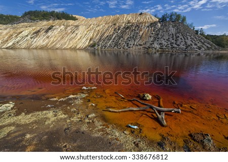 Red artificial lake and hills as a result of mining and production of copper