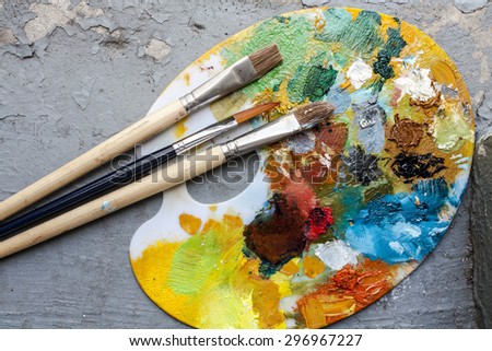Brushes and colorful abstract oil colors painters pallet, on retro background