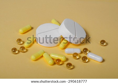A bunch of big white and a lot of little yellow pills. On a yellow background