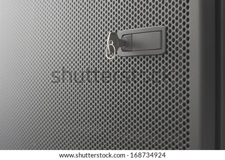 Door  metallic black of server rack cabinet. The key is inserted into the door lock. Side lighting and  shallow DOF