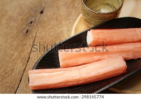 Crab stick in plate on brown background