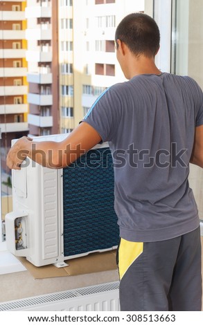 Worker holds the outdoor unit of the air conditioner