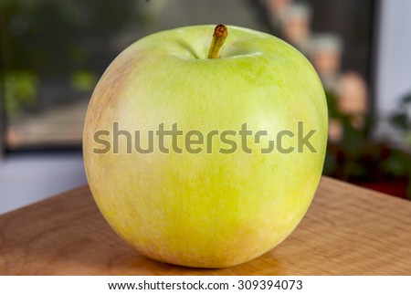 on the edge of the table is a ripe apple