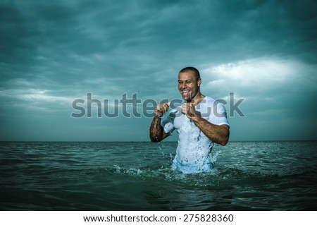 beautiful, strong, happy man in a wet t-shirt, the sea