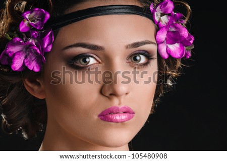portrait of beautiful girl with violet flowers in hair on black