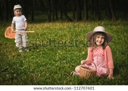 little boy with butterfly net and girl on the grass in the forest, focus on the girl