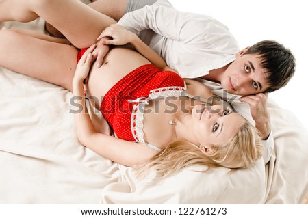 young happy man and pregnant woman lying on bed