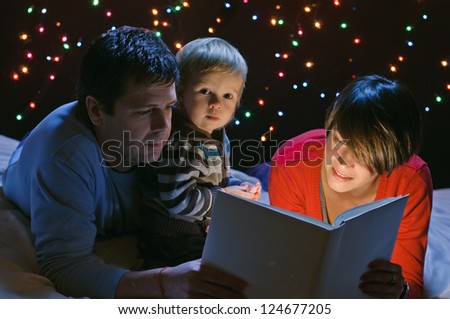 young happy family with light book on garland background