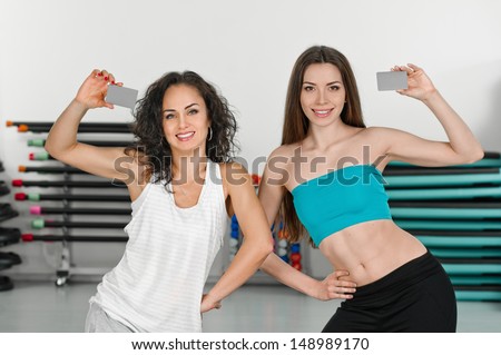 young women shows cards in fitness club