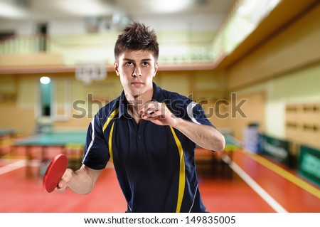 young man tennis-player in play on sport club background