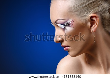 face of young woman with coiffure makeup on blue background