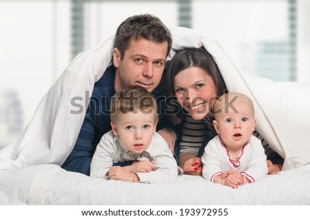 happy family, mother ,father and their baby and boy under the blanket on the bed. Window background