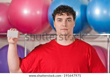 Fitness sign man showing empty blank paper, card. Fitness man at gym.