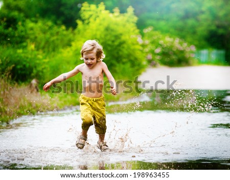 Little boy runs through a puddle. summer outdoor