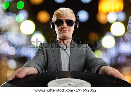 DJ man with vinyl in sunglasses on nightlife lights background