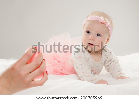 portrait of six month old baby girl in pink dress. on grey background