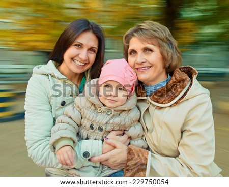 Grandmother with mother and daughter having fun on spinning roundabout. Autumn. Naturally blur motion