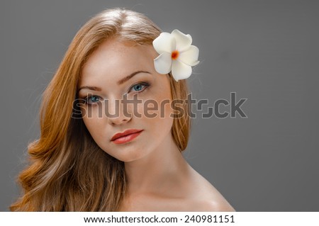 beautiful young redhead woman with freckles portrait isolated on grey background