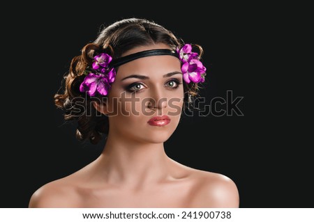 Beauty portrait of young woman with purple floral wreath over dark background