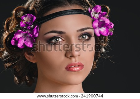Beauty portrait of young woman with purple floral wreath over dark background