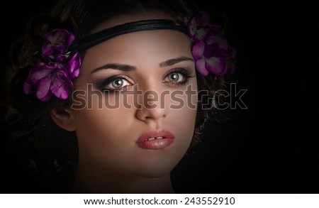 Beauty portrait of young woman with purple floral wreath over dark vignetting background
